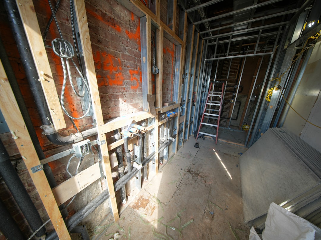 A plumber roughing in supply and drain lines in framed walls of a new house