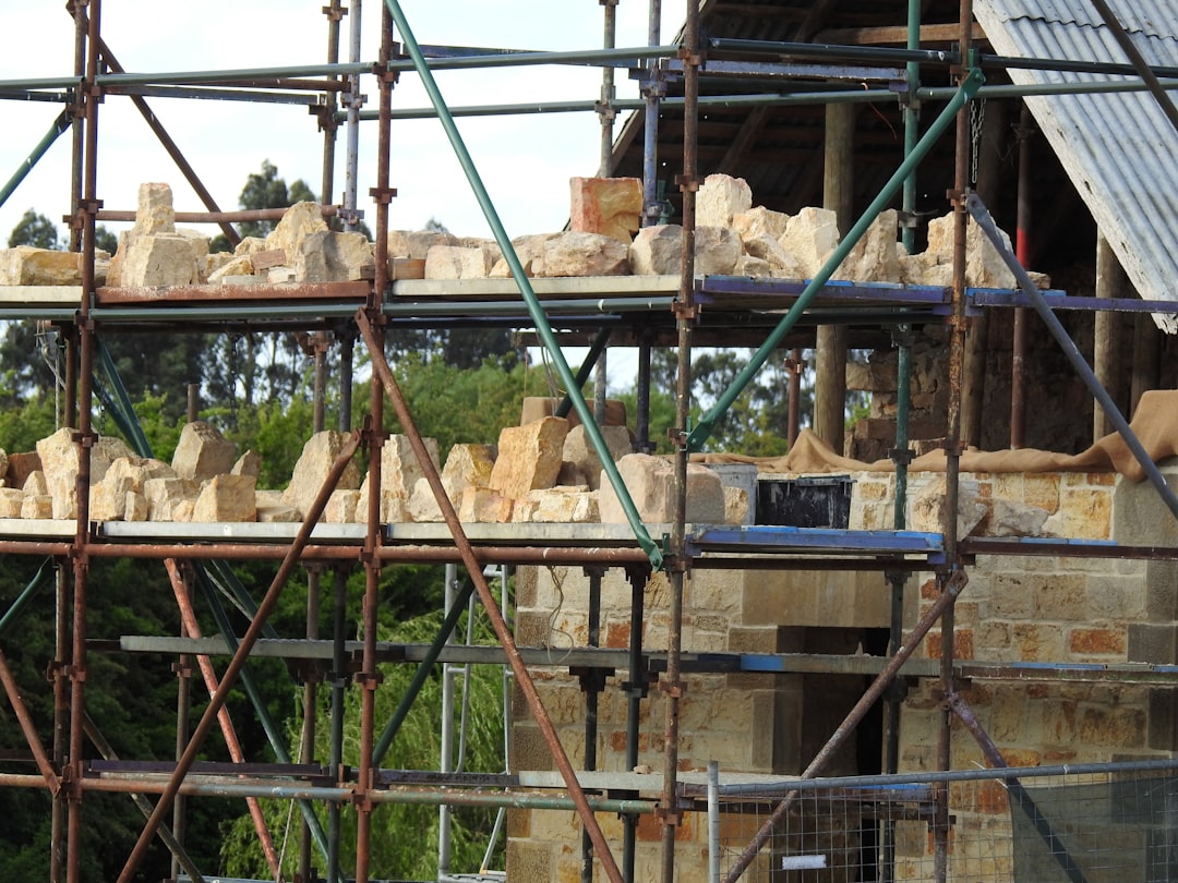 Masonry crew installing brick veneer with scaffolding on a two-story home